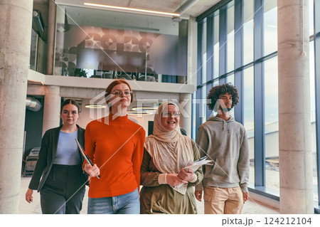 In the sleek corridors of a modern startup office, a diverse group of colleagues, led by their director, confidently stride forward, symbolizing collective success and the journey toward new business 124212104