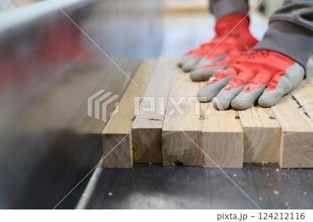 Close Up of Worker Carefully Cutting and Planing Wooden Pieces for Furniture in Wood Industry 124212116