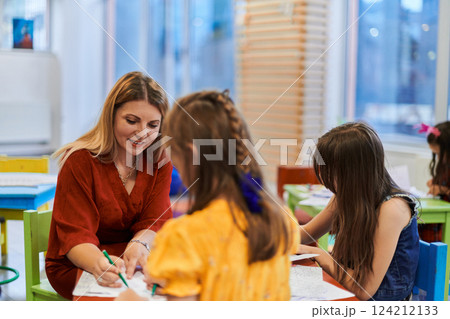 Creative kids during an art class in a daycare center or elementary school classroom drawing with female teacher. Creative kids during an art class in a daycare center or elementary school classroom drawing with female teacher. 124212133