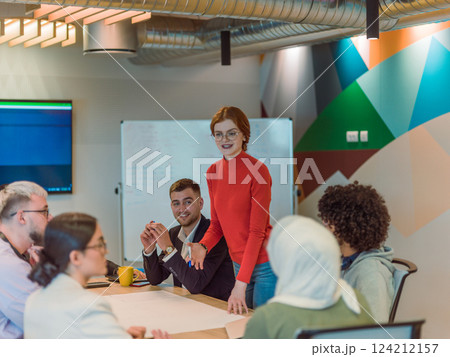 A diverse team of business experts in a modern glass office, attentively listening to a colleague's presentation, fostering collaboration and innovation 124212157