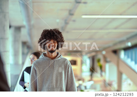 In a modern office environment, an African American young entrepreneur engages in work, while in the background, his dedicated colleagues exemplify teamwork and collaboration, encapsulating the 124212293