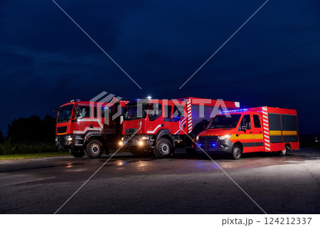 A pair of highly modern and quality fire trucks illuminate the night with their rotating lights, symbolizing the cutting-edge technology and preparedness of the firefighting fleet, ready to respond to 124212337
