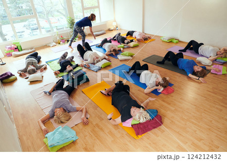 A group of senior women engage in various yoga exercises, including neck, back, and leg stretches, under the guidance of a trainer in a sunlit space, promoting well-being and harmony A group of senior women engage in various yoga exercises, including neck, back, and leg stretches, under the guidance of a trainer in a sunlit space, promoting well-being and harmony 124212432