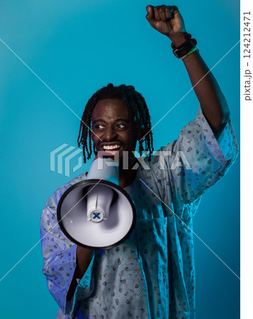 In a powerful and symbolic image, an African American man wears traditional clothing, passionately wields a megaphone against a striking blue background, with his hand raised in the air symbolizing In a powerful and symbolic image, an African American man wears traditional clothing, passionately wields a megaphone against a striking blue background, with his hand raised in the air symbolizing 124212471