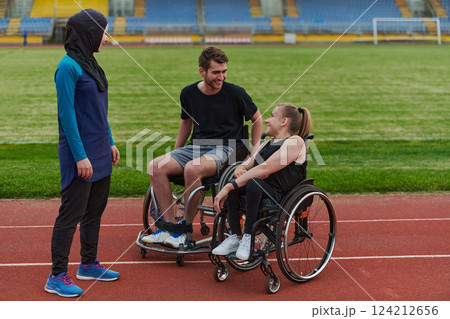 A woman with a disability in a wheelchair talking after training with a woman wearing a hijab and a man in a wheelchair 124212656