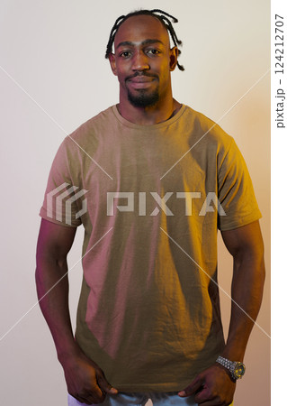 A charismatic and stylish African American man commands attention against a vibrant yellow gel background, showcasing his confident and contemporary fashion sense, radiating charm and sophistication 124212707