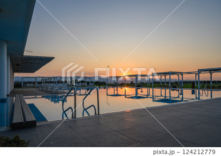 Tranquil sunset reflecting on a serene poolside retreat by the mountains 124212779