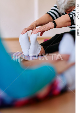 Senior Woman Practicing Back Stretches in a Sunlit Space for Optimal Health and Well Being 124212838