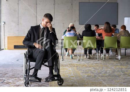 A sad and disheartened director in a wheelchair sitting alone in a large office, reflecting on the challenges and isolation that come with their professional responsibilities 124212851