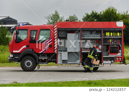 A firefighter meticulously prepares a modern firetruck for a mission to evacuate and respond to dangerous situations, showcasing the utmost dedication to safety and readiness in the face of a fire 124212857