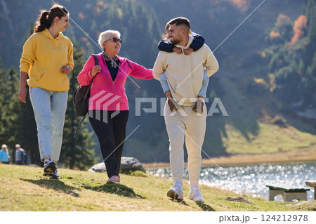 A family shares delightful moments with their friends amid the stunning landscapes of mountains, lakes, and winding paths, promoting a healthy lifestyle and the joy of familial bonds in the embrace of 124212978