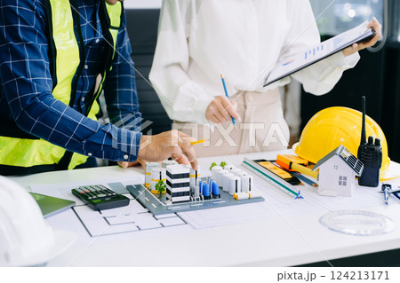 Creative architect projecting on the big drawings with architectural project at construction site at desk in office 124213171
