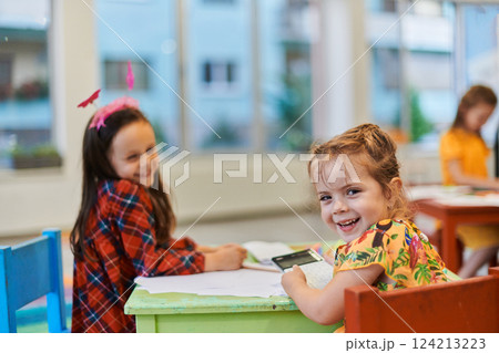 Creative kids during an art class in a daycare center or elementary school classroom drawing with female teacher. 124213223