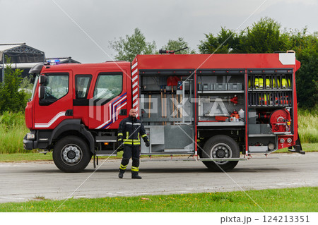 A firefighter meticulously prepares a modern firetruck for a mission to evacuate and respond to dangerous situations, showcasing the utmost dedication to safety and readiness in the face of a fire 124213351