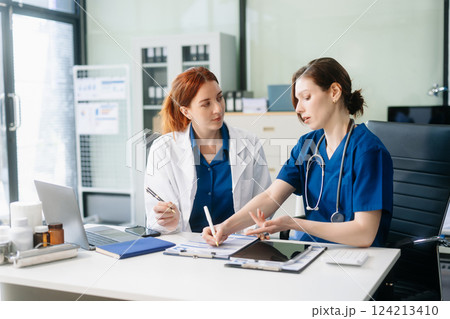 Doctors and nurses collaborating in a modern medical office, showcasing teamwork and patient care. 124213410