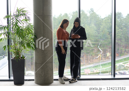 Two colleagues are having a productive conversation while looking at a tablet. Two colleagues are having a productive conversation while looking at a tablet. 124213582