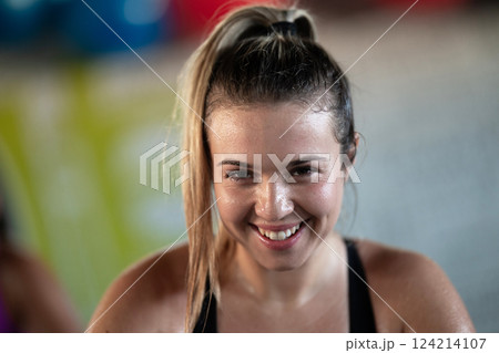 A fit and determined woman takes a short break during an intense workout session at the gym, showcasing strength and perseverance. 124214107