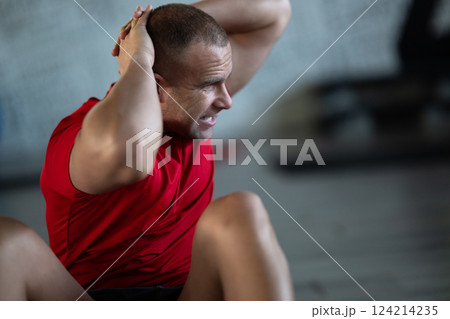 A muscular man performing crunches in the gym, focusing on building core strength and achieving his fitness goals A muscular man performing crunches in the gym, focusing on building core strength and achieving his fitness goals 124214235
