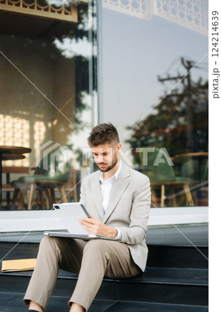 Modern businessman outdoors, using a tablet. Ideal for business, technology, and innovation themes. Modern businessman outdoors, using a tablet. Ideal for business, technology, and innovation themes. 124214639