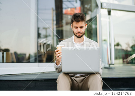 Handsome unshaven businessman walking with laptop, tablet and smartphone on city Handsome unshaven businessman walking with laptop, tablet and smartphone on city 124214768