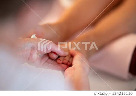 Foot Massage Therapy in a Relaxing Spa Setting. A professional massage therapist in a white uniform provides a soothing foot massage to a client in a calm and serene spa environment 124215110
