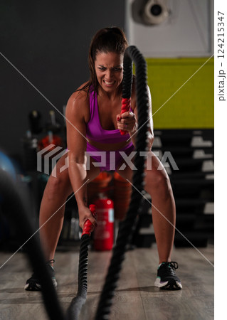 Fit Woman Performing Rope Conditioning Exercise in the Gym 124215347