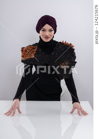 A stylish Muslim woman in a hijab presents her innovative handmade fashion accessory crafted from dried plums in a professional studio. A stylish Muslim woman in a hijab presents her innovative handmade fashion accessory crafted from dried plums in a professional studio. 124215676