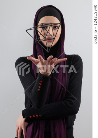 Elegant Muslim woman in a hijab with a geometric structure in a conceptual portrait. Elegant Muslim woman in a hijab with a geometric structure in a conceptual portrait. 124215940