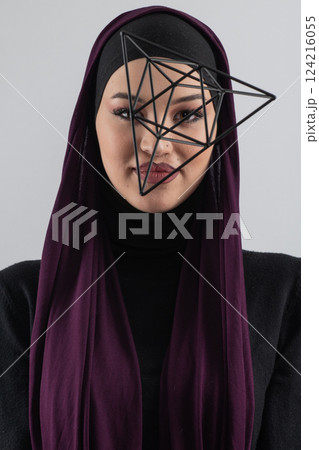 Elegant Muslim woman in a hijab with a geometric structure in a conceptual portrait. 124216055