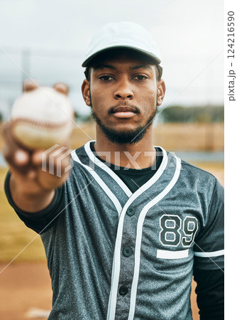 Baseball, sports and ball with a black man athlete on a grass pitch or field before a game for fitness and exercise. Training, workout and health with a male baseball player ready for a game outside 124216590