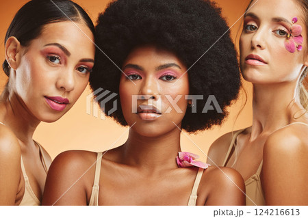 Diversity, beauty and women with flowers for makeup, skincare and cosmetics. Skincare products, spa wellness and group of girls portrait in orange studio with pink orchids for natural beauty products 124216613