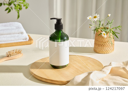 A circular wooden tray lined under unbranded plastic bottles. A beige burlap fabric placed randomly, a wicker vase contains white flowers. A natural wooden comb with wide teeth used for head massage 124217097