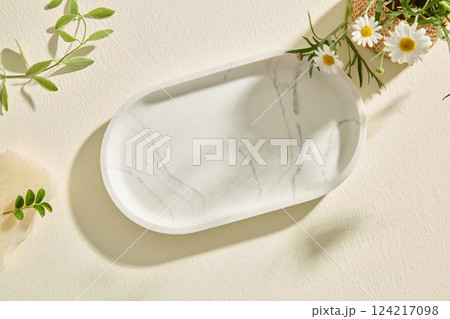 Top view of an oval marble tray presented on white background. Empty marble tray is used to hold the product and design. Branches and flowers around are used for decoration. Empty space for text. 124217098