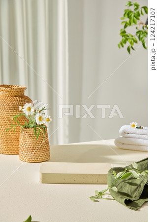 White wooden tray in the center, with empty space to display products and designs. Green canvas with leaves placed on top. Rattan flower vases placed around for decoration. Minimalist concept. 124217107
