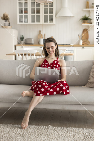 Happy millennial woman using notebook on sofa at comfortable kitchen 124217748