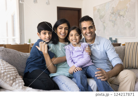 Indian couple and kids relaxing on couch posing for camera Indian couple and kids relaxing on couch posing for camera 124217871
