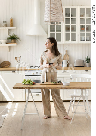 Happy young woman cook healthy food at kitchen using smartphone Happy young woman cook healthy food at kitchen using smartphone 124217888