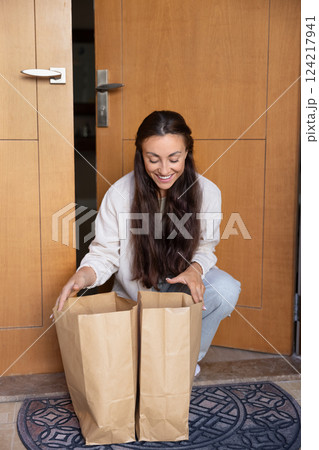 Happy young woman receiving order from online supermarket delivery service Happy young woman receiving order from online supermarket delivery service 124217941