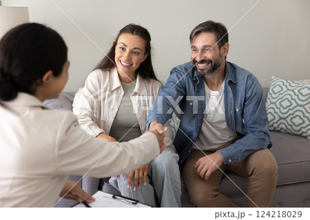 Positive couple of homeowners shaking hands with financial adviser 124218029
