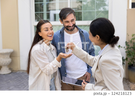 Couple of house buyers receiving key from real estate agent 124218123
