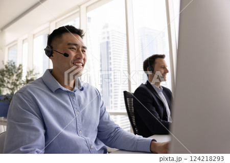 Happy Asian contact center employee man using computer and headset 124218293