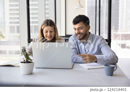 In open-space office two teammates working on joint online project 124218401