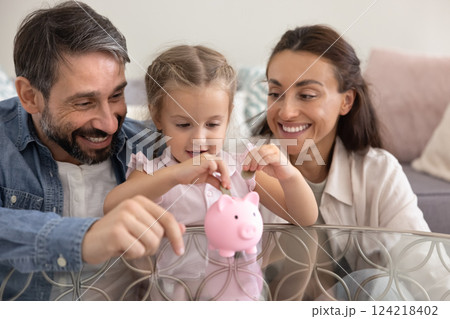 Happy parents training little kid girl to save money 124218402