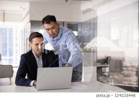 Focused diverse business colleagues discussing online application workv Focused diverse business colleagues discussing online application workv 124218446