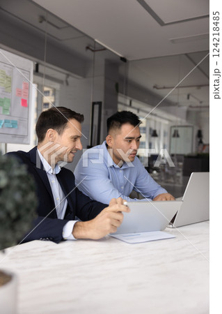 Two diverse male business colleagues working together at laptop 124218485