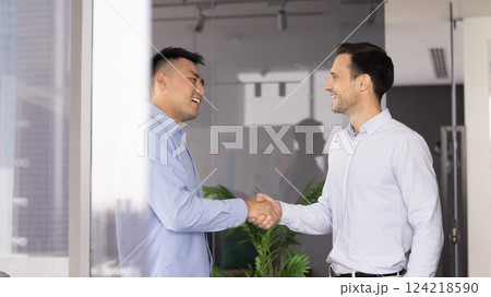 Two happy successful multiethnic businessmen giving handshake in office 124218590