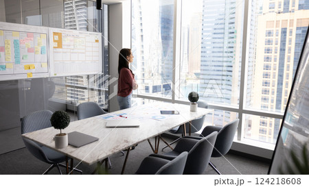 Thoughtful young business leader woman standing alone in office 124218608