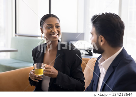 African businesswoman holds mug, leads pleasant talk with colleague 124218644