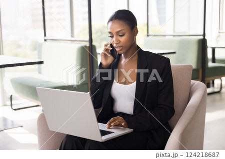 Businesswoman talk on smartphone using laptop seated in coworking 124218687