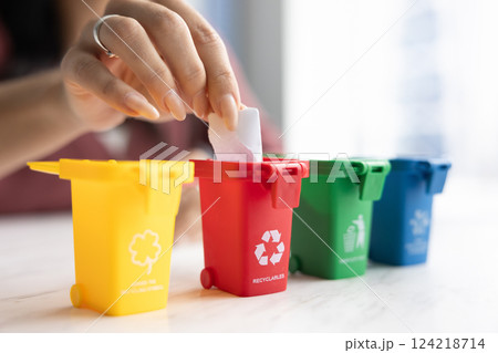 Woman promoting waste sorting, putting garbage into toy trash bins Woman promoting waste sorting, putting garbage into toy trash bins 124218714
